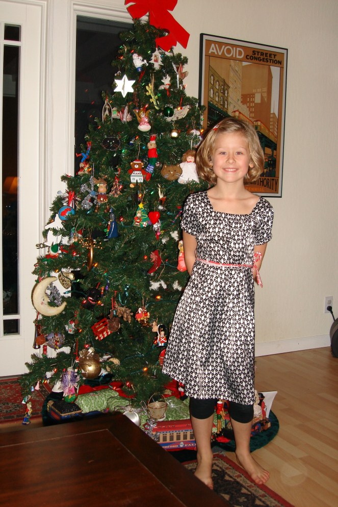 A girl standing in front of a decorated Christmas tree